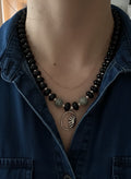 Person wearing an onyx beaded necklace with a blue denim jacket