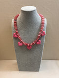 Necklace with pink heart-shaped beads on a gray mannequin bust against a beige background