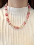 Necklace with pink and white beads on a person wearing a white ribbed top.