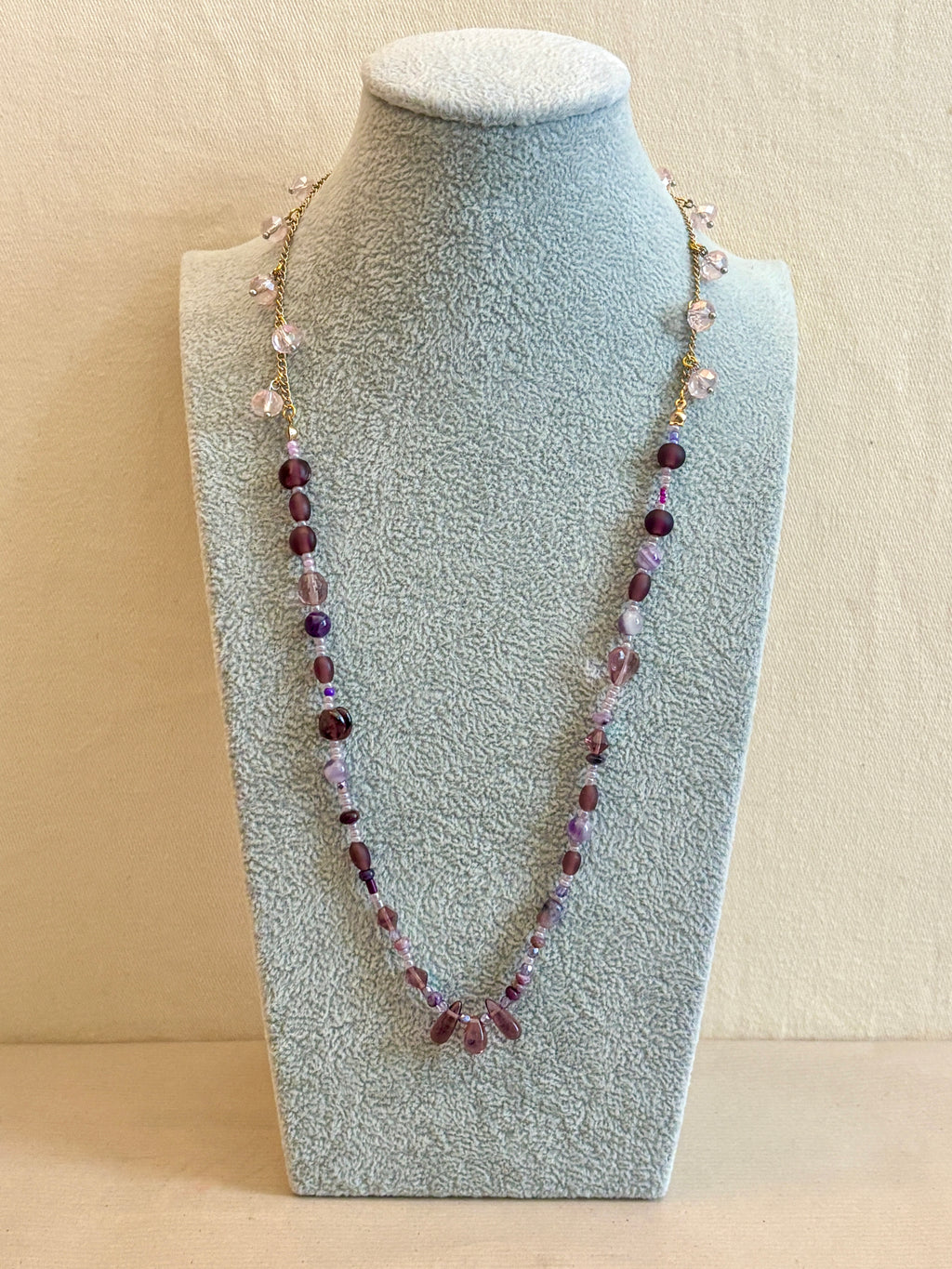 Beaded necklace on a gray bust against a beige background