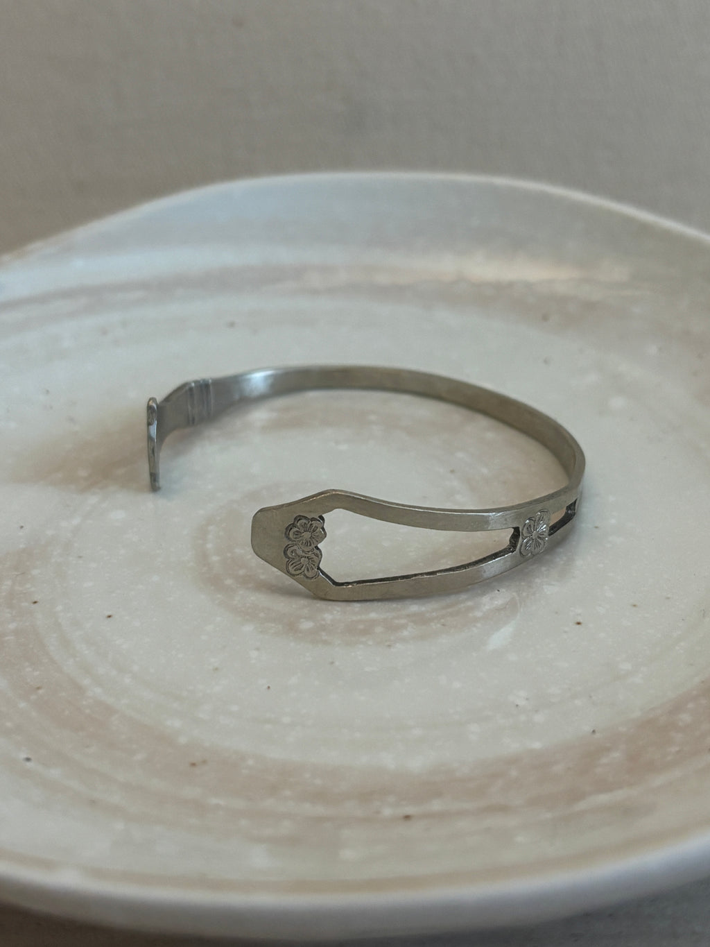 Metallic bangle on a textured beige surface