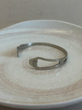Metallic bangle on a textured beige surface