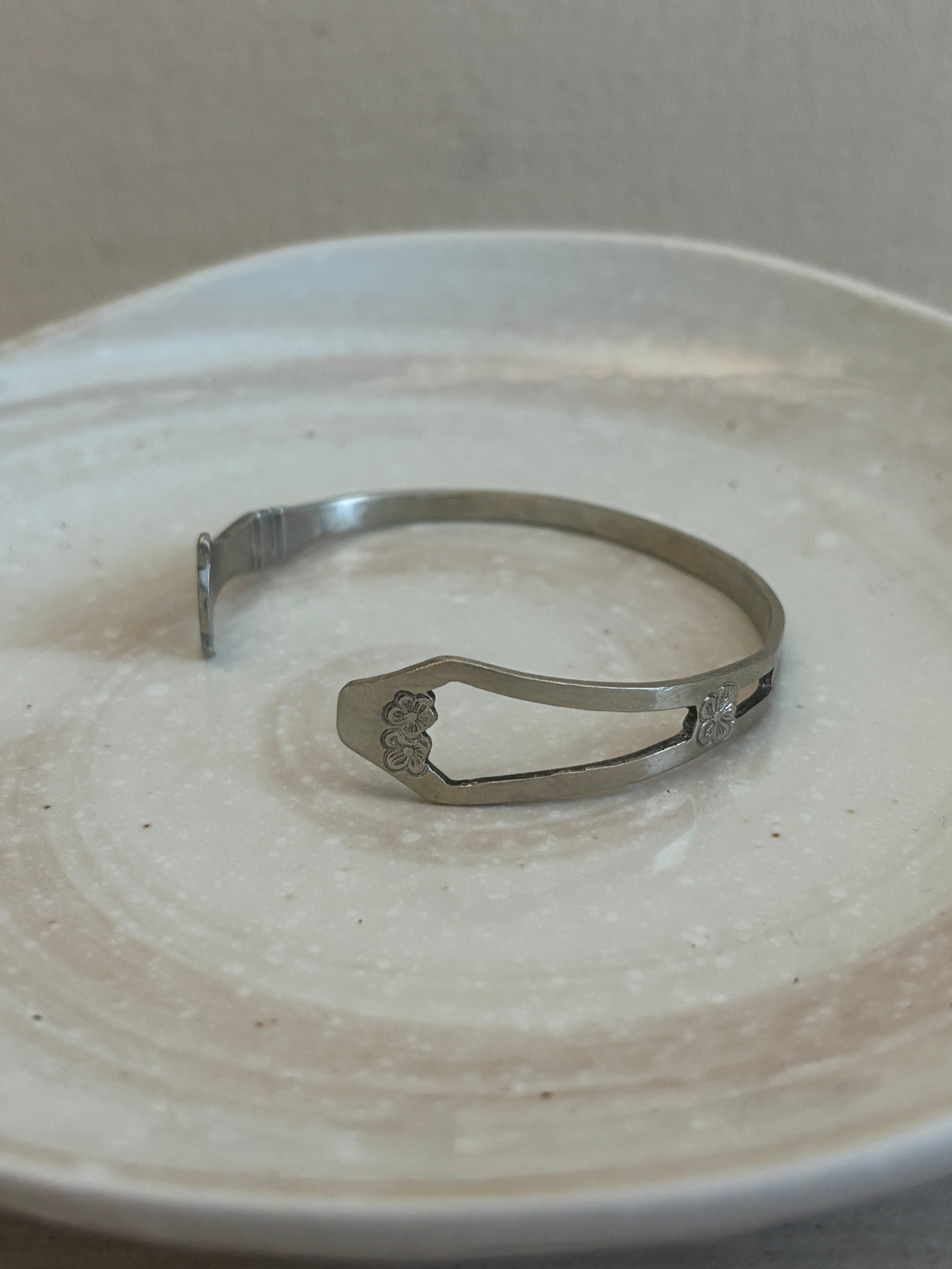 Metallic bangle on a textured beige surface
