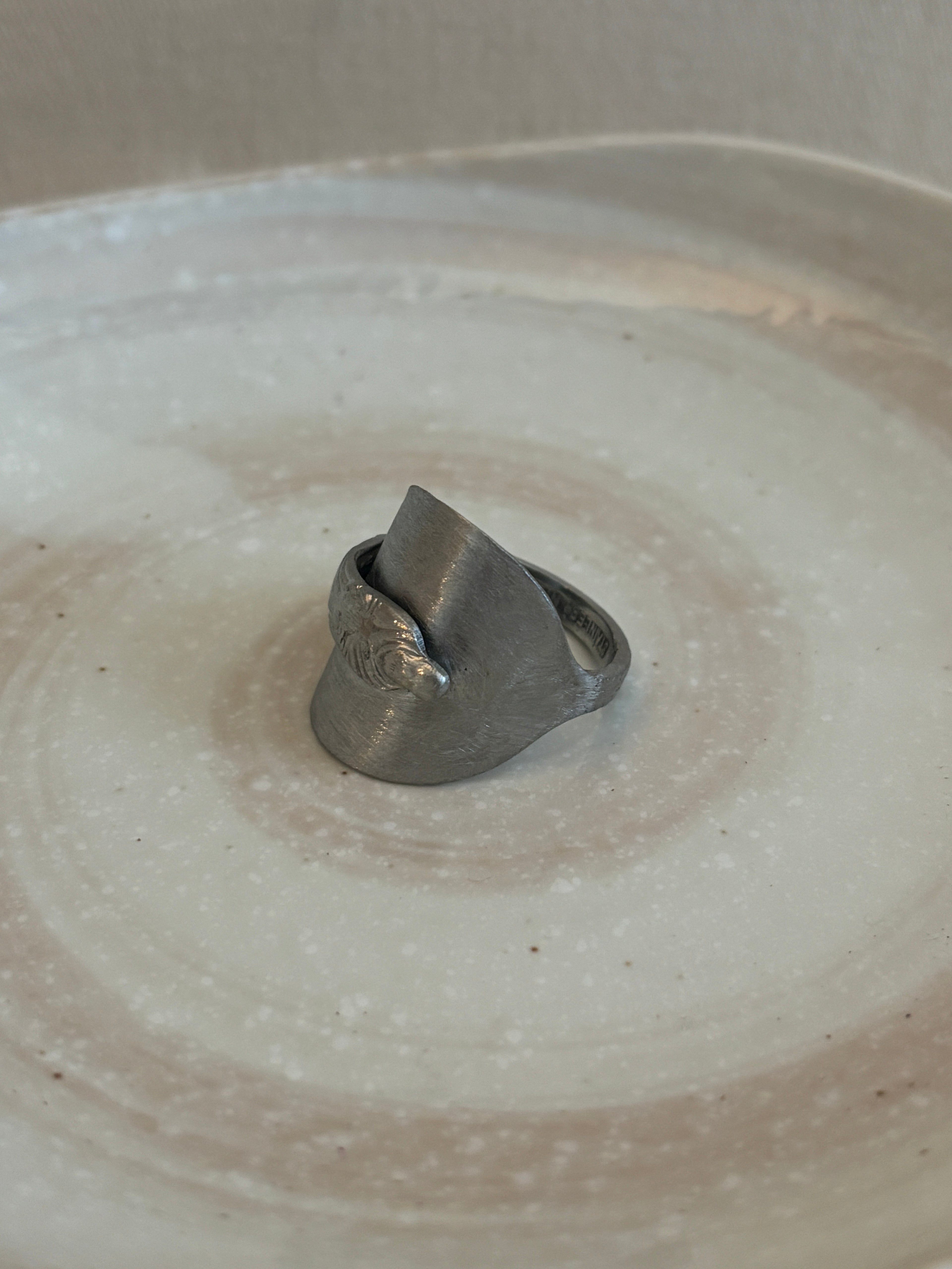 silver ring on a textural ceramic plate