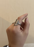 Hand wearing a silver ring on a plain background