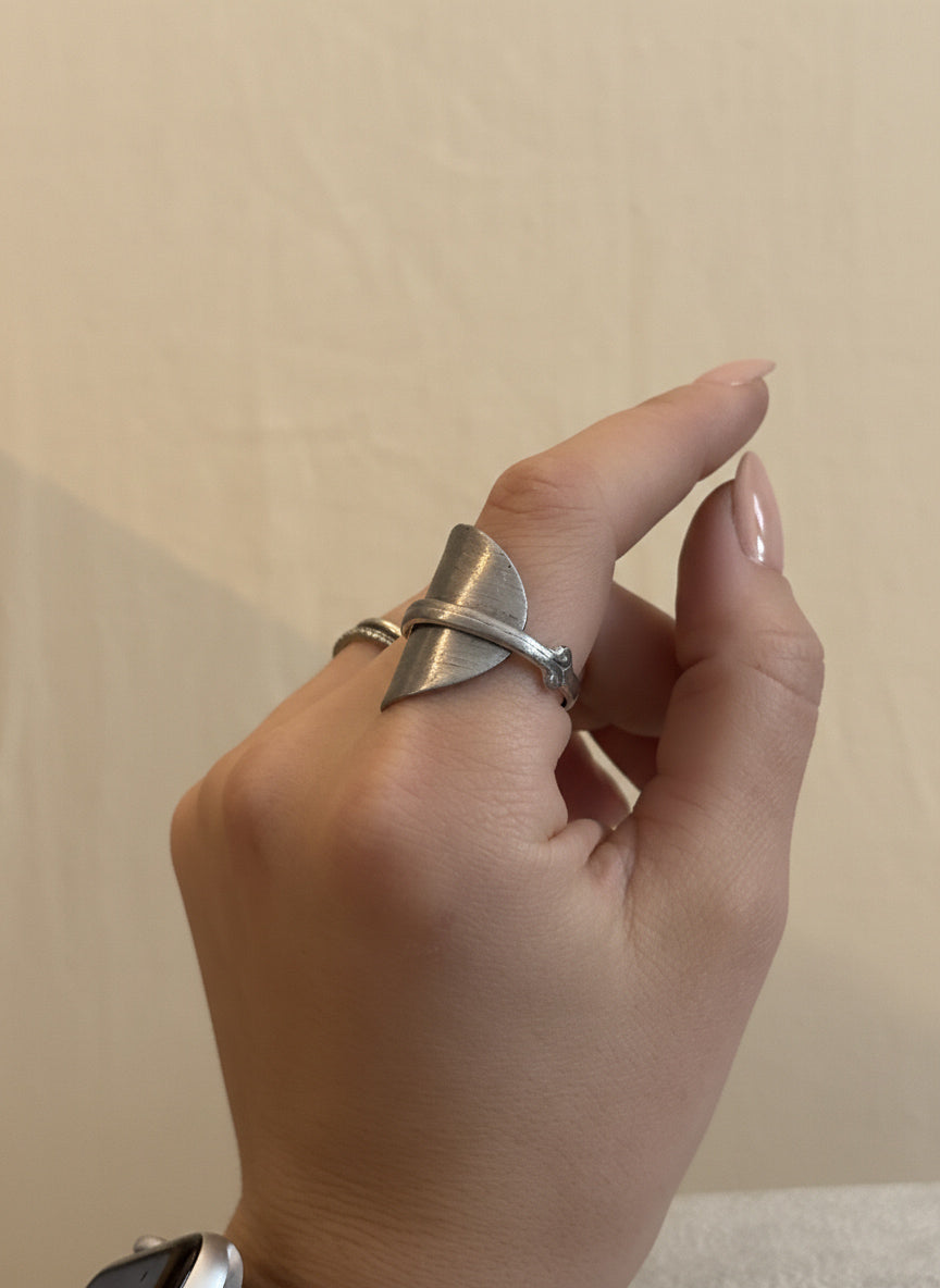 Hand wearing a silver ring on a plain background