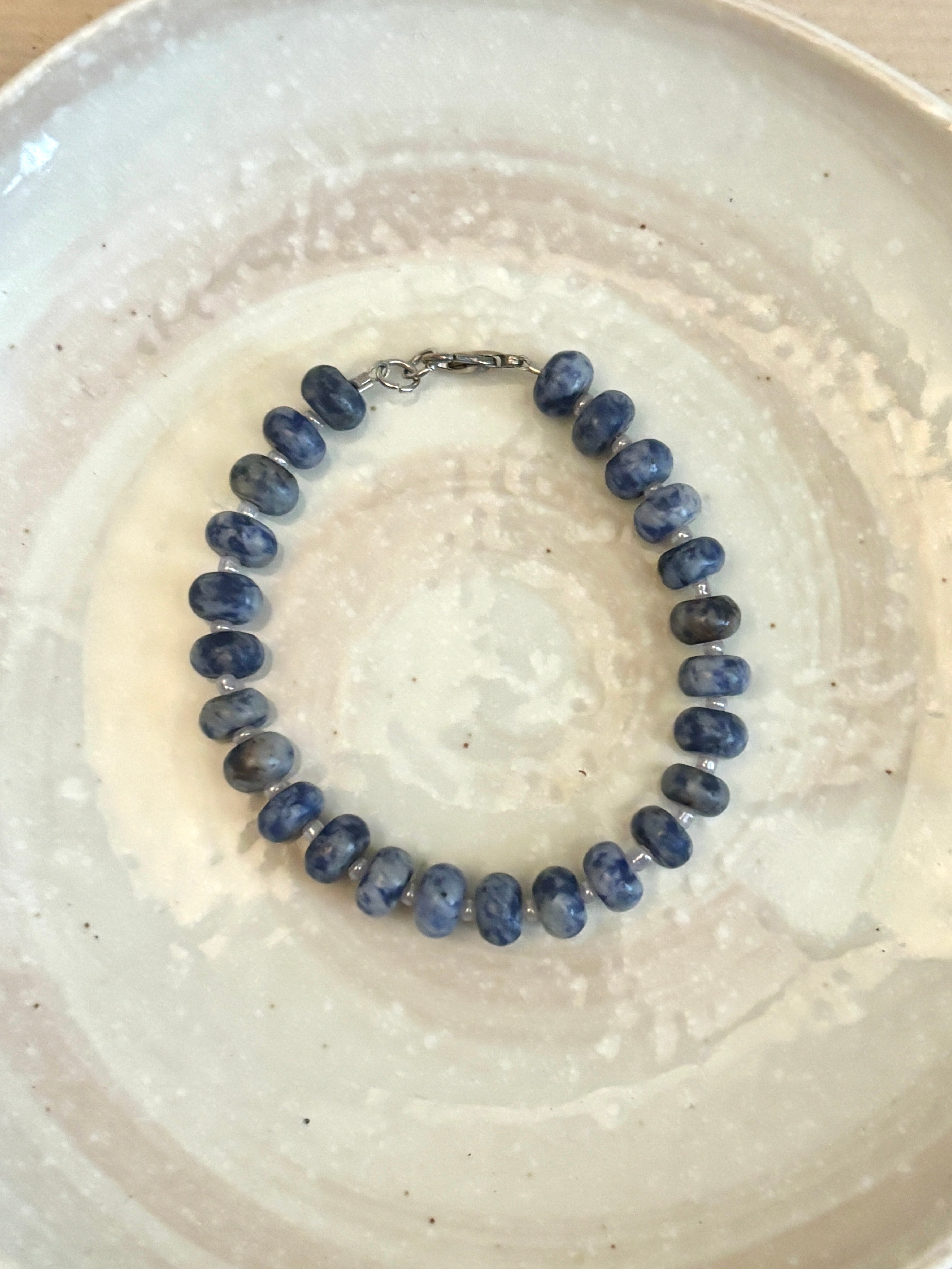 Blue beaded bracelet on a white ceramic plate
