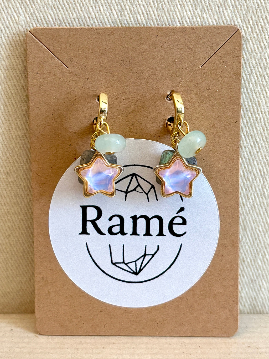 Star-shaped earrings with gold accents on a Ramé branded card.