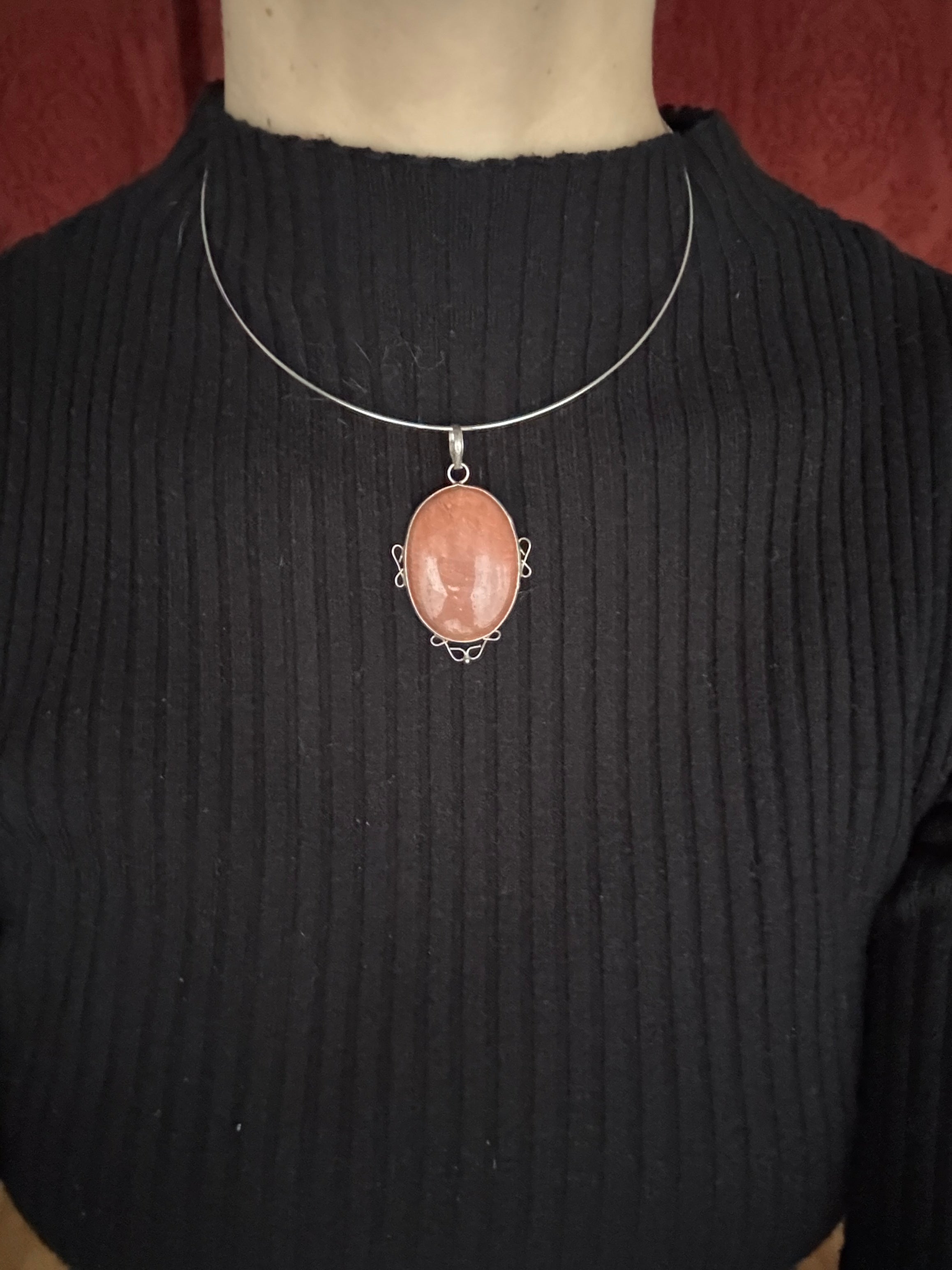 Necklace with a pink stone pendant on a black shirt