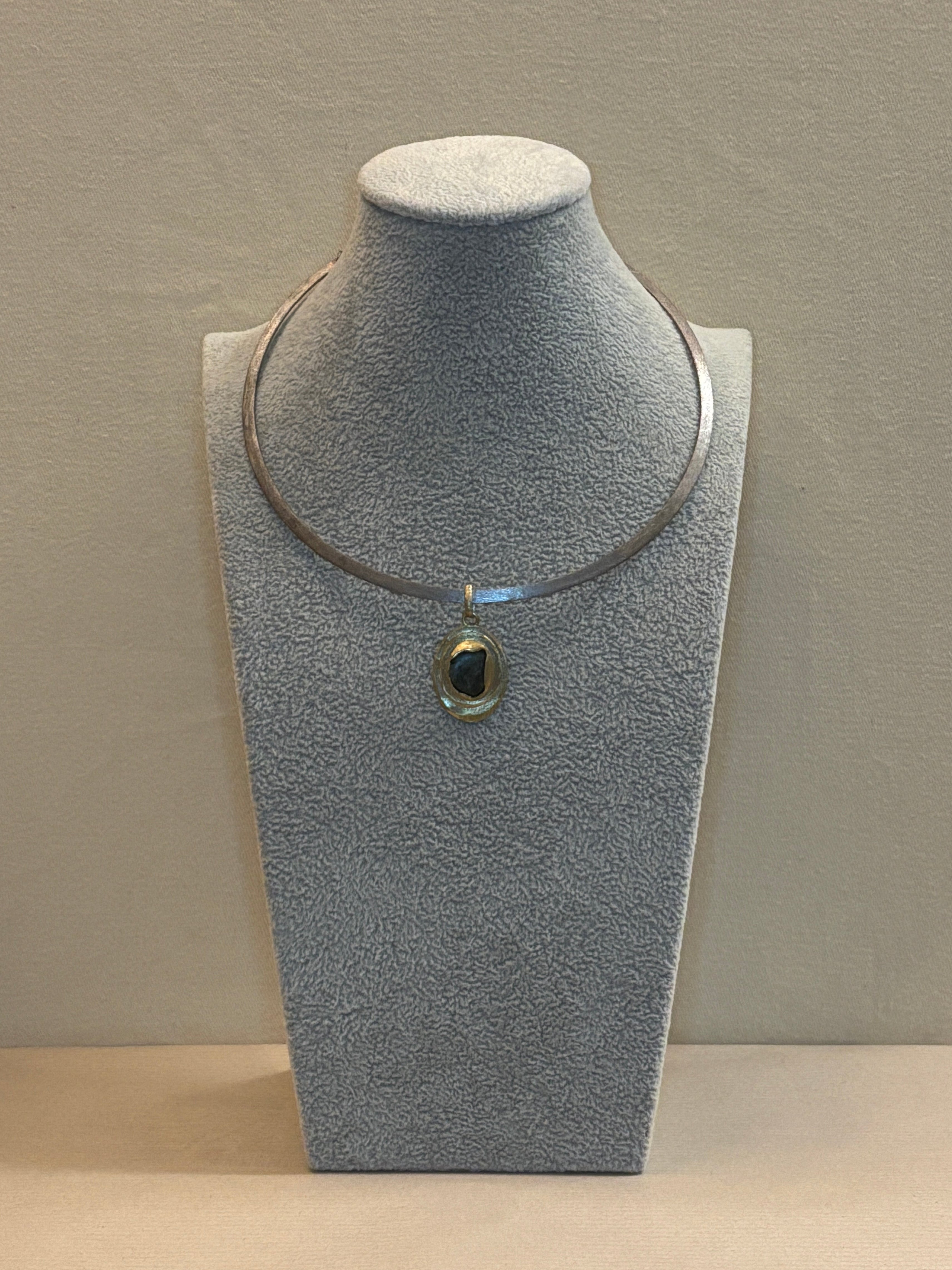 Pendant necklace on a grey jewelry display.