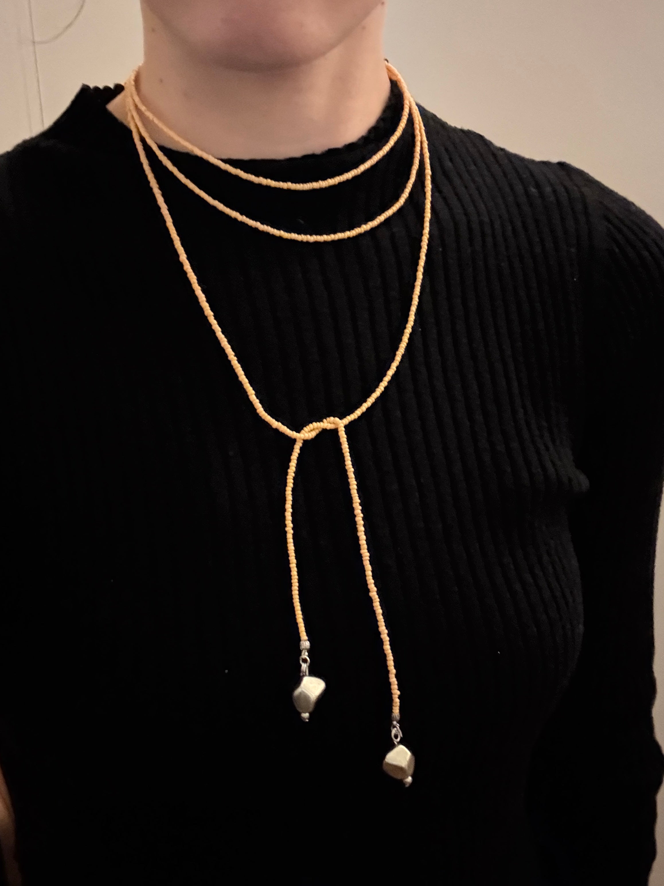Black garment with beaded necklace on a plain background