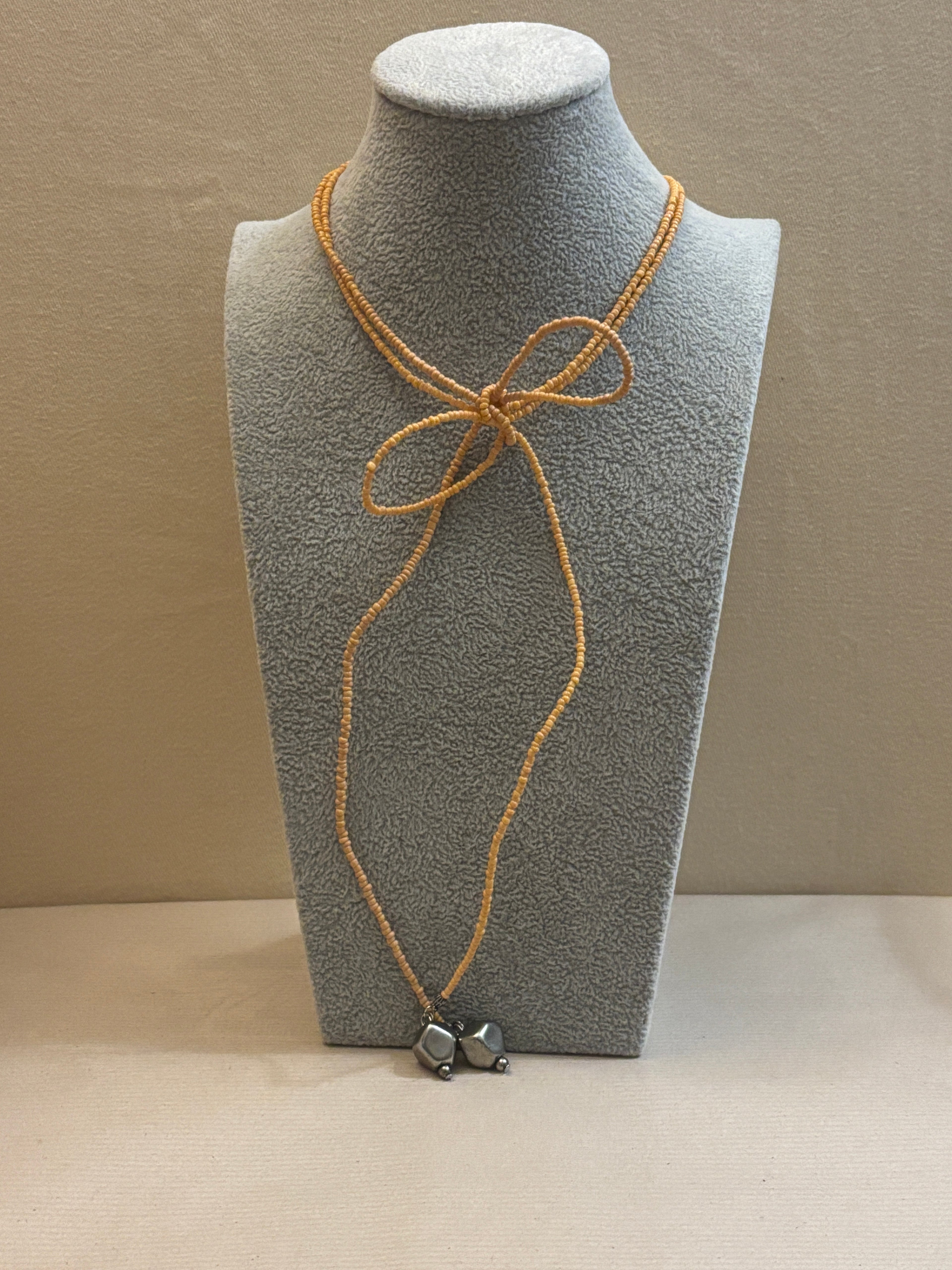 Gray textured panel with beaded cord and decorative elements on a beige background